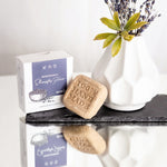 Festes Shampoo für stumpfes Haar von Wolkenlos Kosmetik neben weißer Vase mit Blümchen